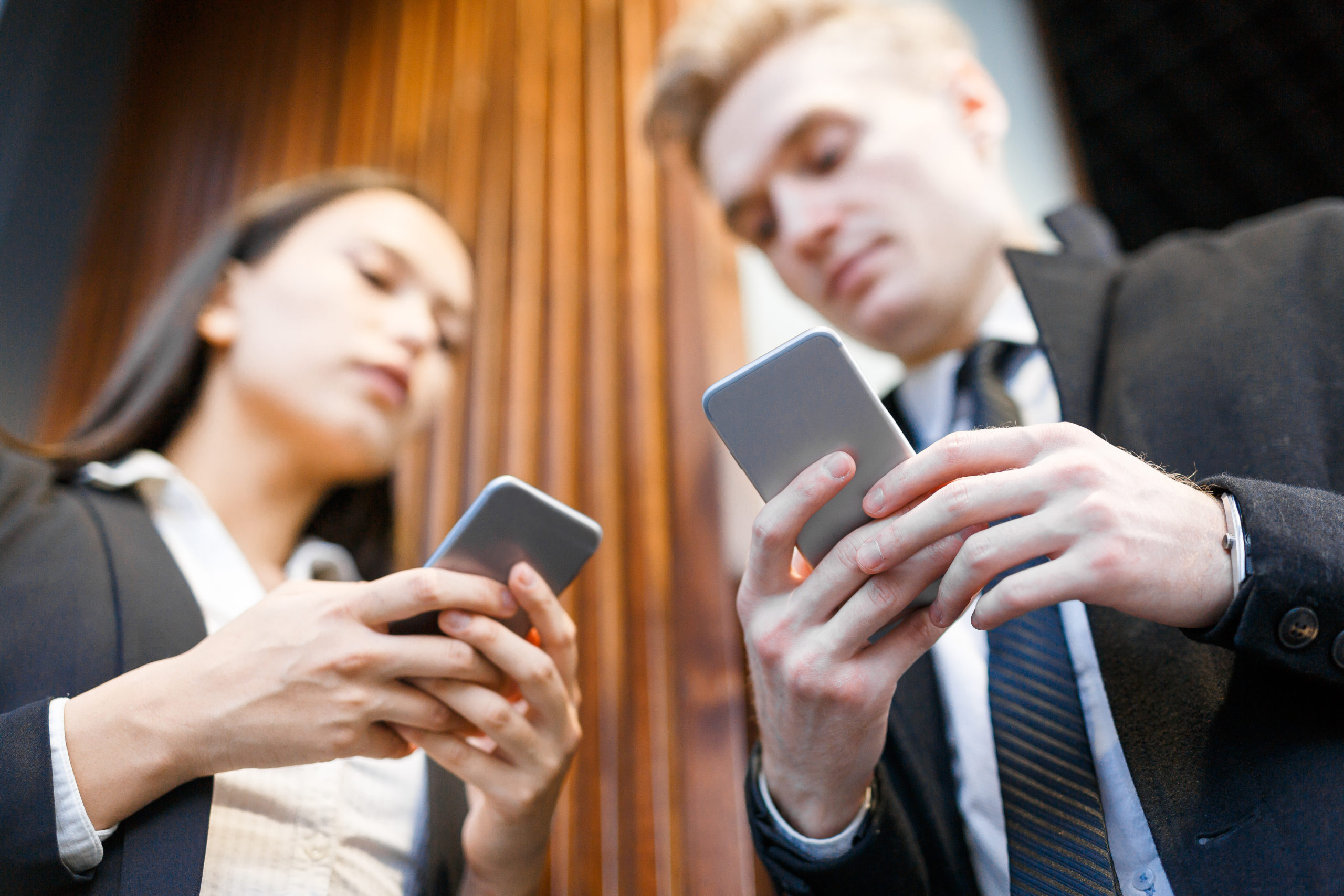 Modern man and woman communicating by messaging in smartphones